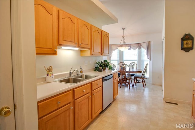 kitchen featuring dishwasher, a sink, light countertops, decorative light fixtures, and baseboards