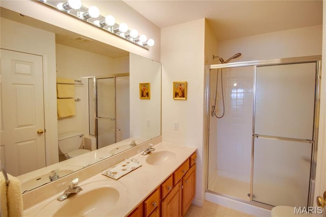 bathroom featuring toilet, a shower stall, and double vanity