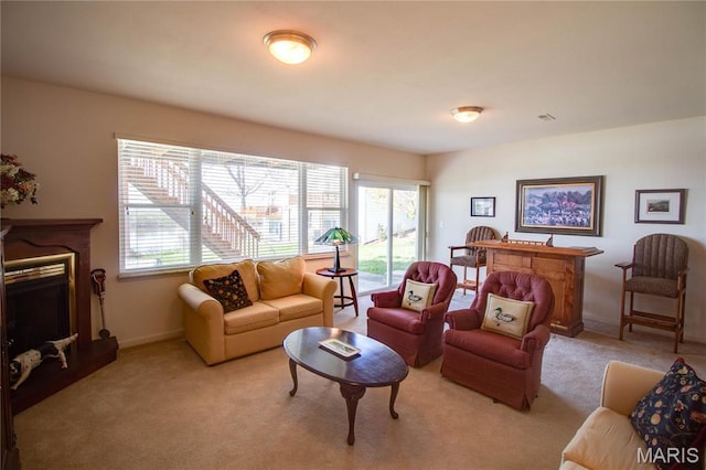 living area featuring a fireplace, light carpet, and baseboards