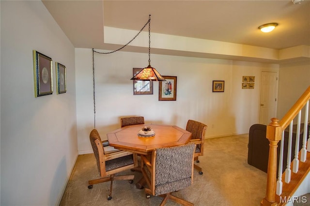 dining area featuring carpet flooring, baseboards, and stairway