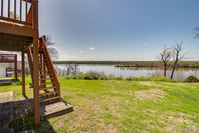view of grassy yard with stairway and a water view