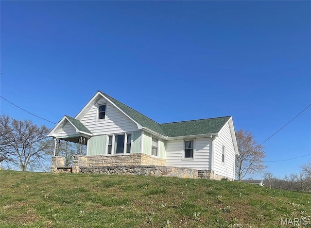 view of front of house with roof with shingles and a front lawn