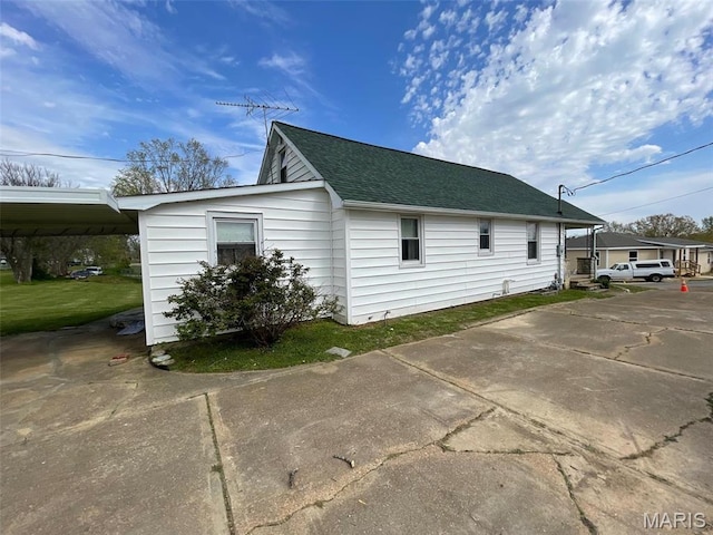 view of side of property with roof with shingles and a carport