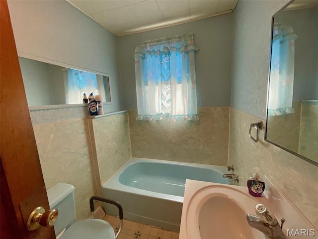full bathroom featuring a bath, toilet, tile patterned flooring, wainscoting, and tile walls