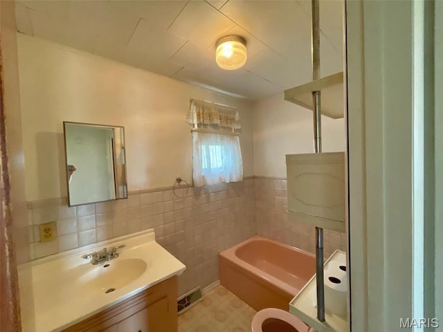 full bath featuring a bath, vanity, tile walls, a wainscoted wall, and a stall shower