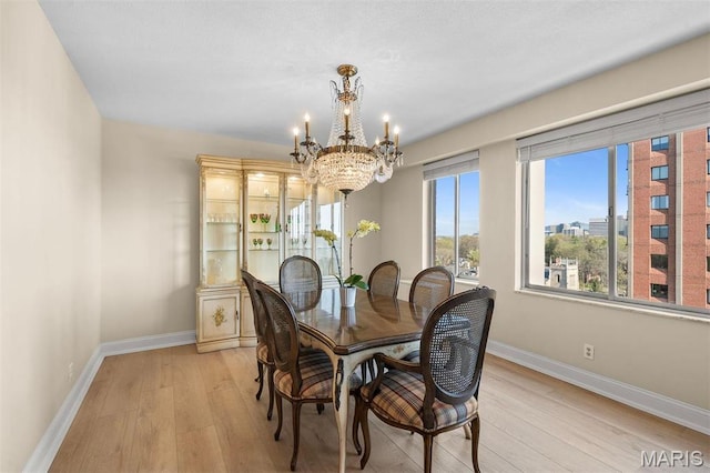 dining area featuring a chandelier, light wood-style flooring, and baseboards