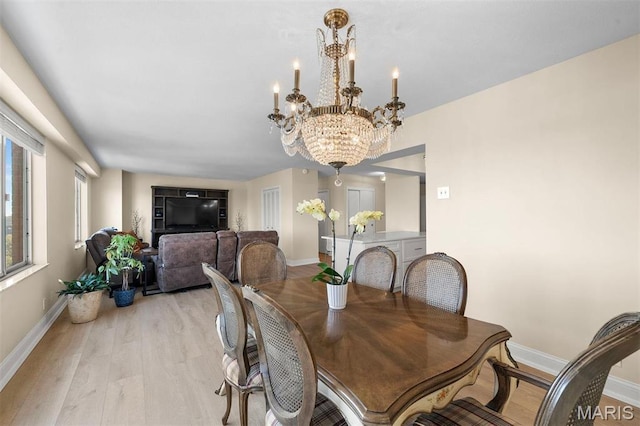 dining room featuring baseboards, a chandelier, and light wood finished floors
