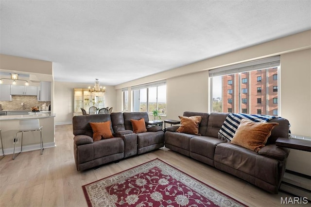 living area featuring a chandelier, light wood finished floors, and baseboards