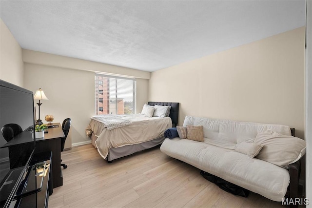 bedroom with light wood-style floors, a desk, and baseboards