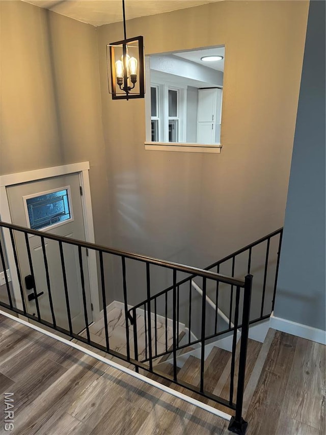 stairway with wood finished floors and a chandelier
