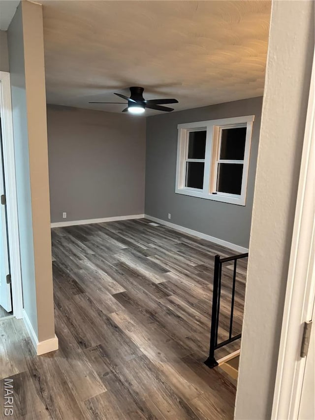 unfurnished room with ceiling fan, dark wood-style floors, and baseboards
