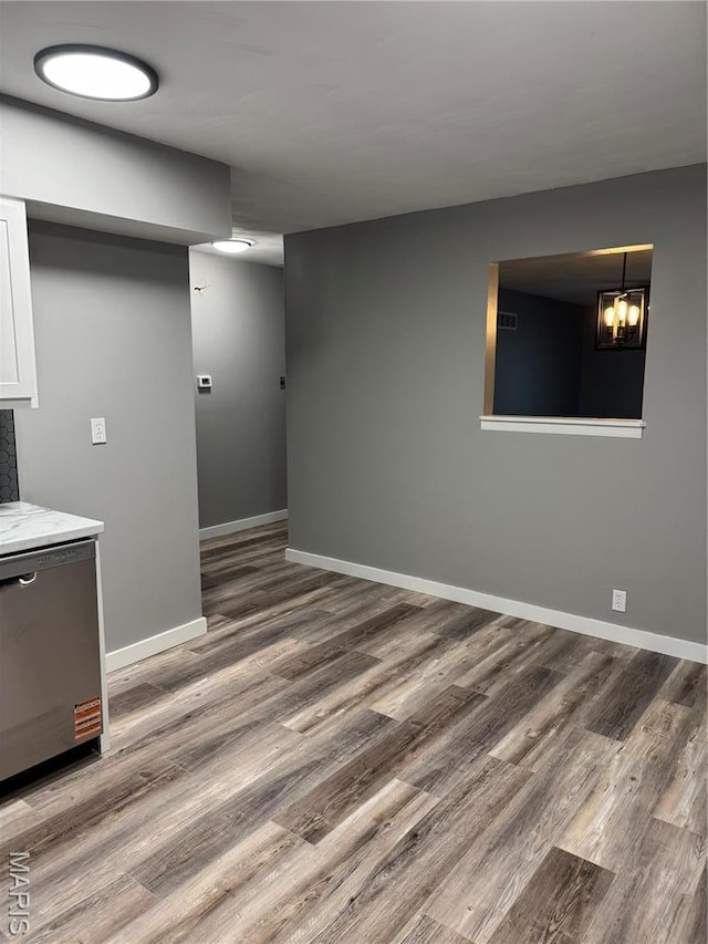 basement featuring wood finished floors, baseboards, and a chandelier