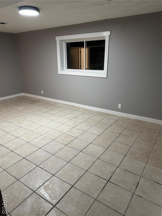 spare room with baseboards and light tile patterned floors