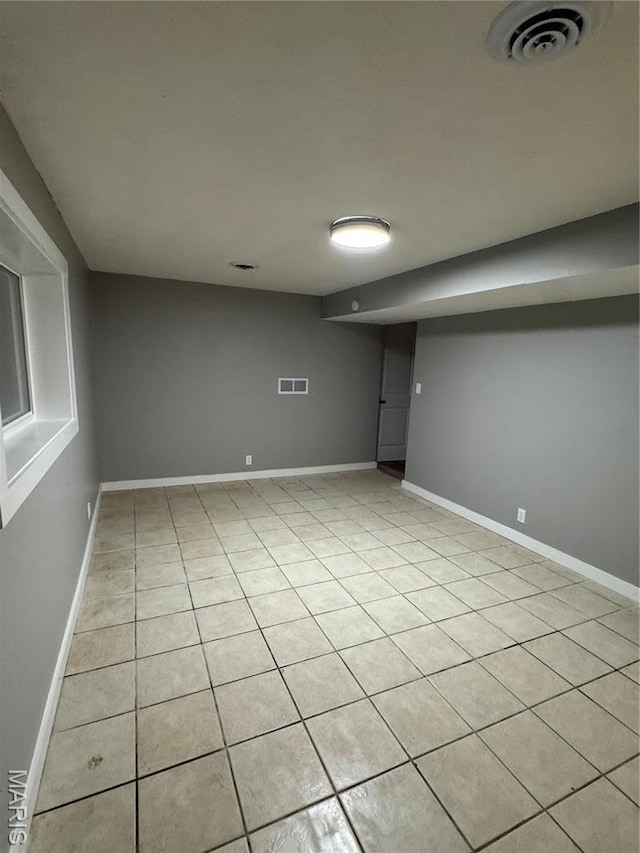 finished basement featuring baseboards and light tile patterned floors