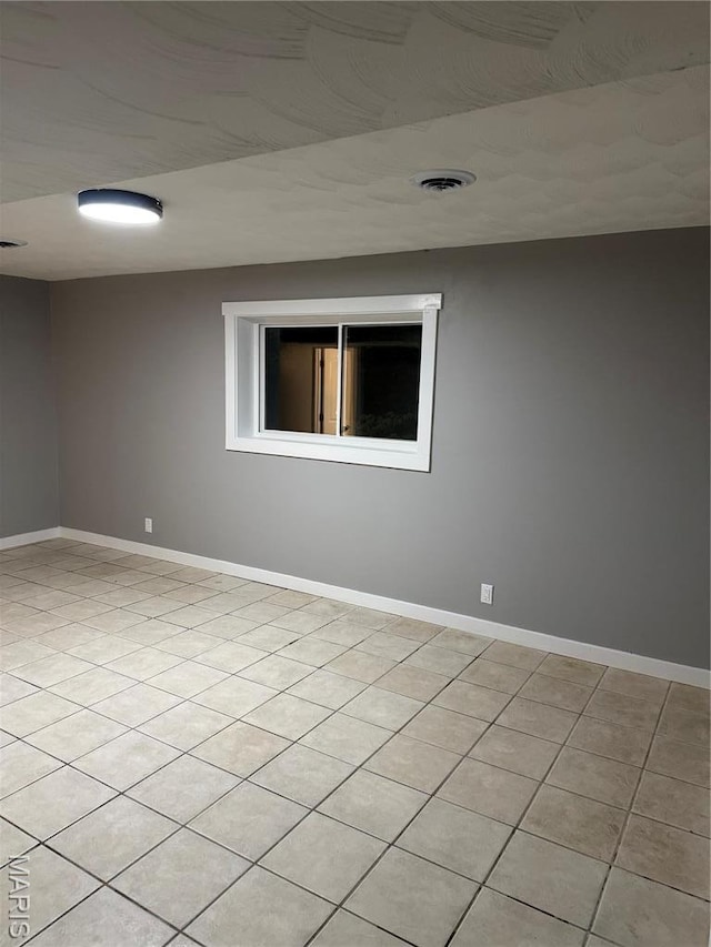 empty room featuring baseboards and light tile patterned floors