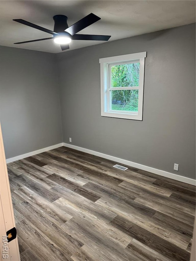 empty room with ceiling fan, dark wood-style floors, and baseboards