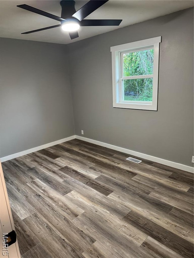 empty room with a ceiling fan, dark wood-style floors, and baseboards