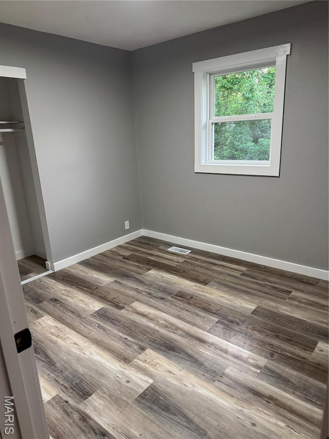 unfurnished bedroom with dark wood finished floors, baseboards, and a closet