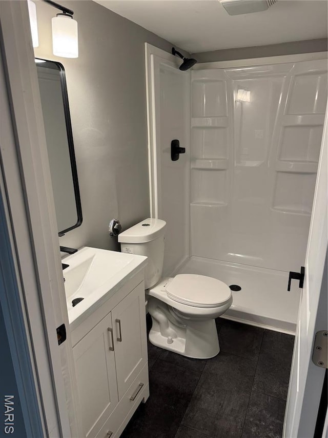 bathroom featuring tile patterned flooring, a shower stall, toilet, and vanity