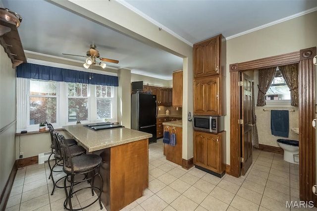 631 N Geyer Rd, Saint Louis, MO 63122 - kitchen with freestanding refrigerator, stainless steel microwave, a baseboard radiator, ornamental molding, and ceiling fan