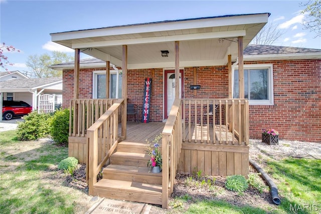 property entrance featuring brick siding, covered porch, and a shingled roof