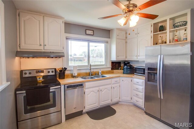 kitchen with stainless steel appliances, a sink, under cabinet range hood, white cabinetry, and light countertops
