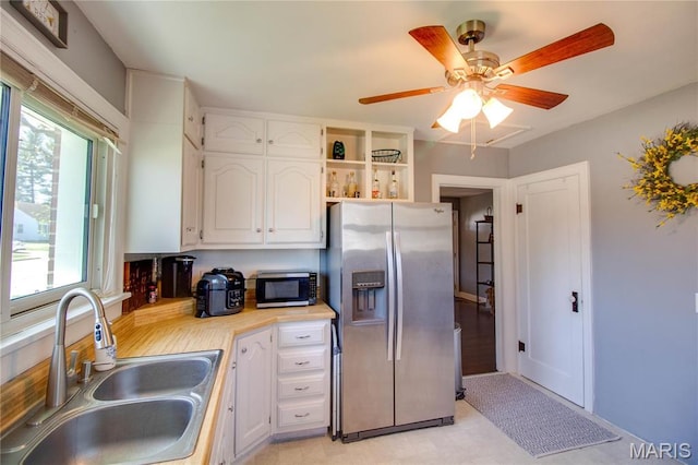 kitchen featuring appliances with stainless steel finishes, a sink, white cabinets, and ceiling fan