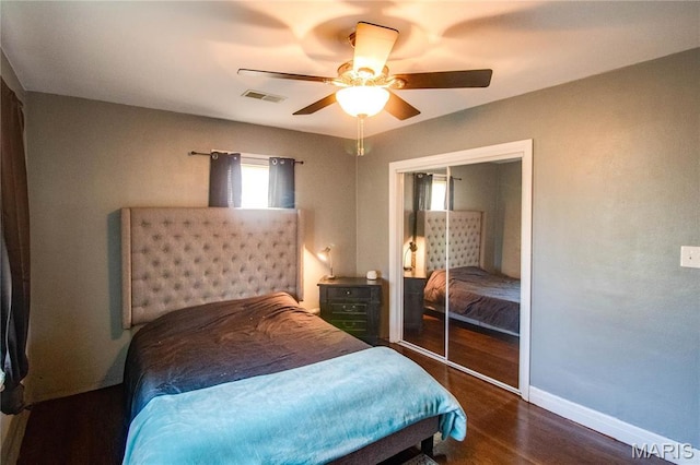 bedroom featuring wood finished floors, baseboards, a ceiling fan, and a closet