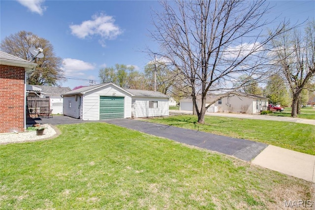 view of front of house featuring an outdoor structure, a front yard, asphalt driveway, and a garage