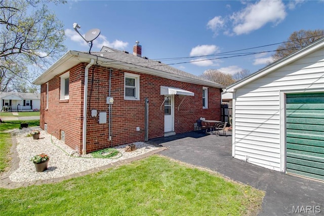 rear view of house with brick siding, a chimney, and a patio area