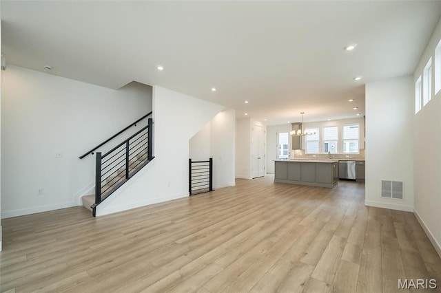 unfurnished living room with a chandelier, light wood-style floors, recessed lighting, baseboards, and stairs