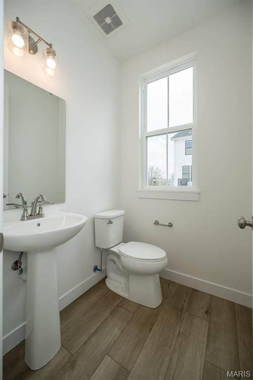bathroom with toilet, wood finished floors, and baseboards