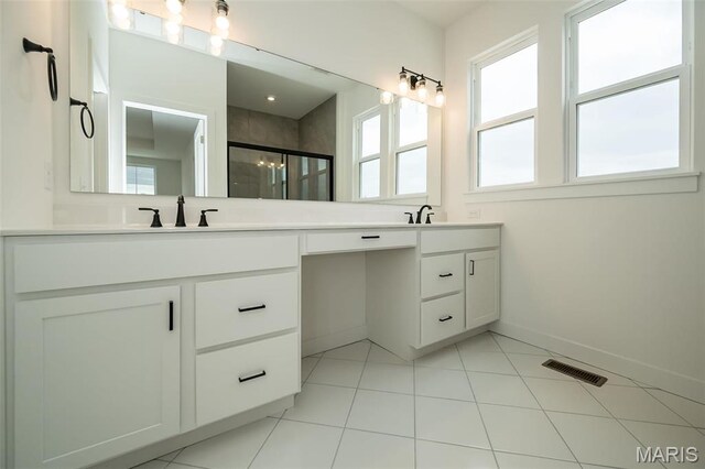 bathroom with double vanity, baseboards, a shower stall, and tile patterned flooring
