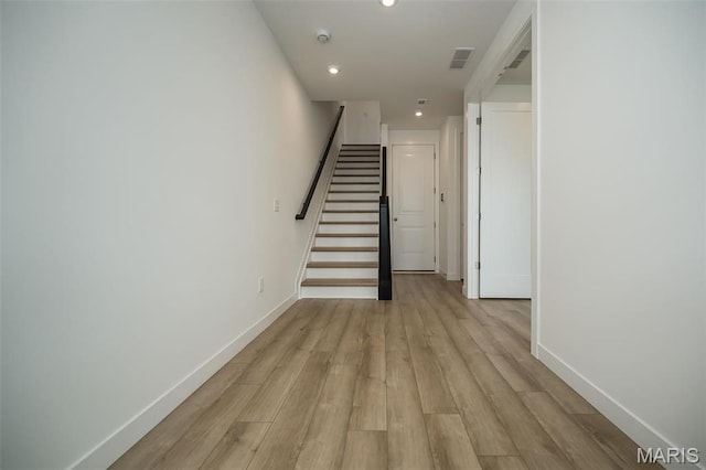 staircase with baseboards, wood finished floors, and recessed lighting