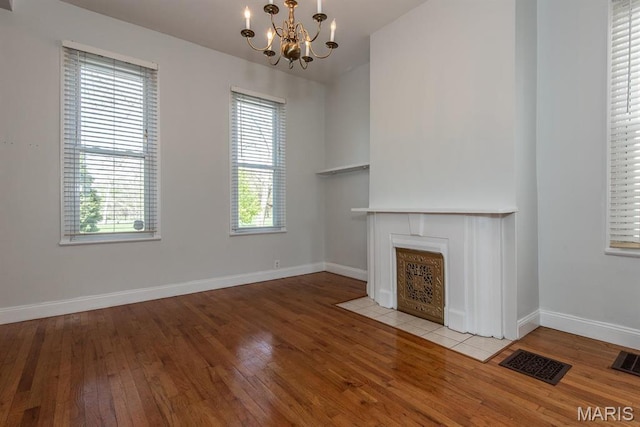 4340 Arsenal St, Saint Louis, MO 63116 - unfurnished living room with a chandelier, wood-type flooring, baseboards, and a fireplace with flush hearth