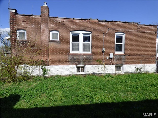 5086 Arlington Ave, Saint Louis, MO 63120 - view of side of home featuring brick siding, a yard, and a chimney