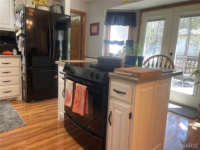 4101 Juedeman Rd, Mo, MO 65453 - kitchen featuring black appliances, light wood-type flooring, white cabinets, a center island, and french doors