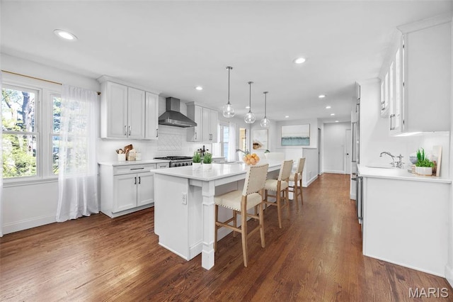 1304 Brynnwood Dr, Saint Louis, MO 63124 - kitchen featuring a center island, wall chimney range hood, white cabinets, light countertops, and tasteful backsplash