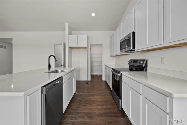 kitchen featuring stainless steel appliances, a sink, dark wood-type flooring, white cabinets, and a center island with sink