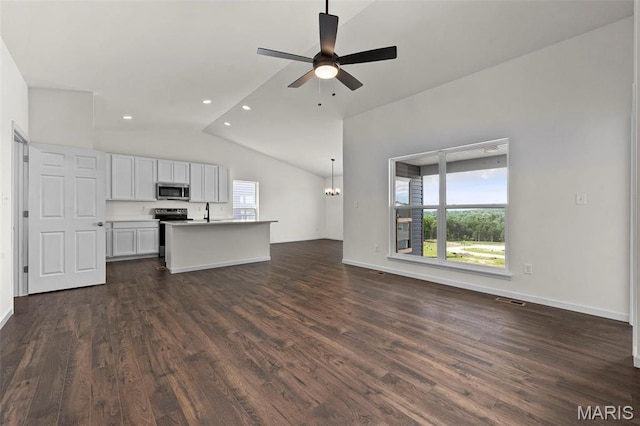 unfurnished living room featuring lofted ceiling, dark wood-style floors, a ceiling fan, baseboards, and a chandelier