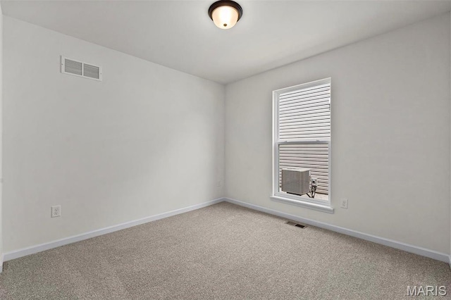 spare room featuring light colored carpet and baseboards