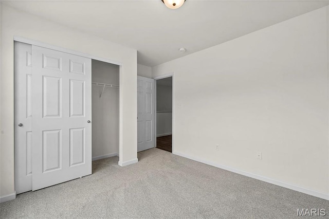 unfurnished bedroom featuring baseboards, carpet floors, and a closet