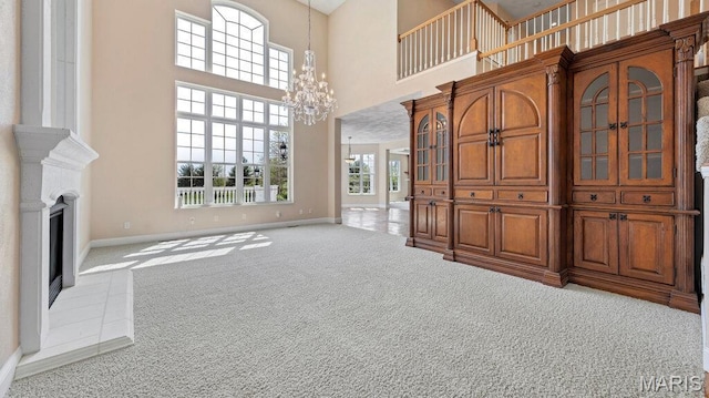 9108 Wiltshire Dr, Columbia, IL 62236 - unfurnished living room featuring a towering ceiling, carpet floors, baseboards, a chandelier, and a fireplace with raised hearth