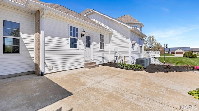 9108 Wiltshire Dr, Columbia, IL 62236 - back of property with entry steps, central air condition unit, a patio, and a shingled roof