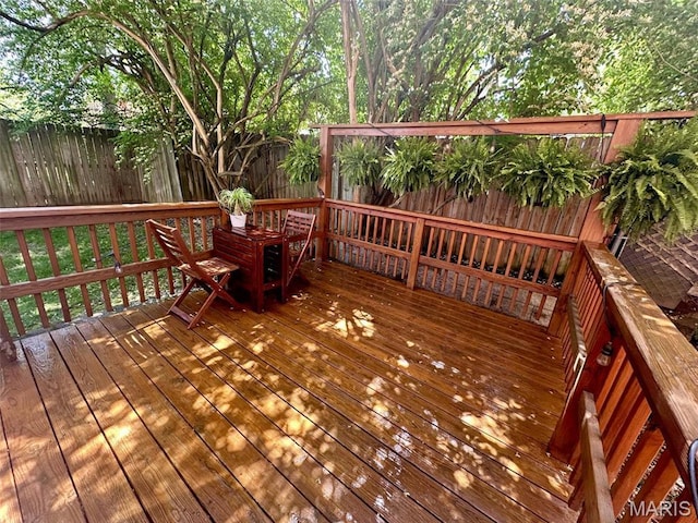 wooden terrace with a fenced backyard