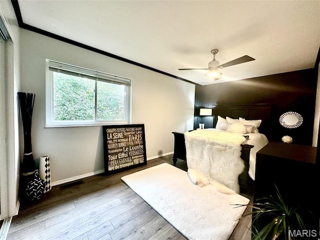bedroom with ornamental molding, wood finished floors, baseboards, and ceiling fan