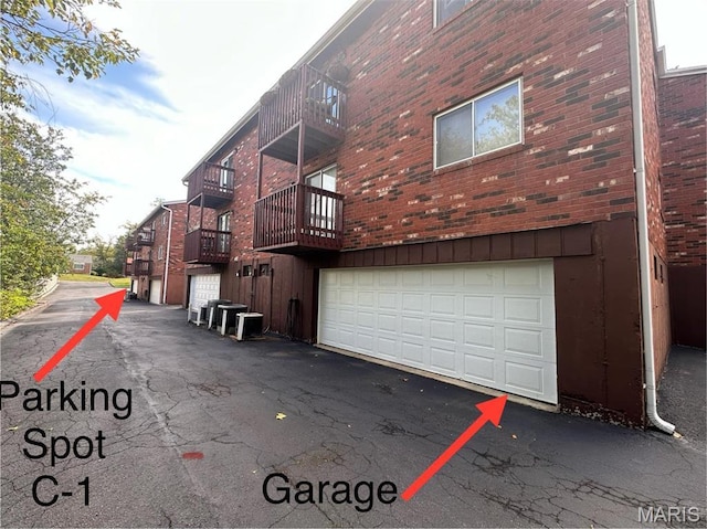 view of property exterior with a garage, asphalt driveway, and brick siding