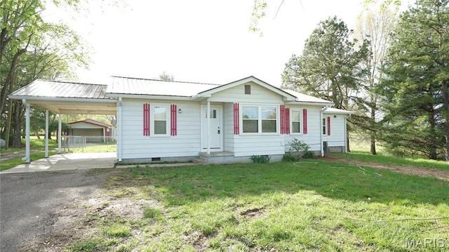 view of front of home featuring dirt driveway, a front lawn, an attached carport, and metal roof