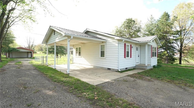 view of property exterior featuring crawl space, metal roof, an outbuilding, and a garage