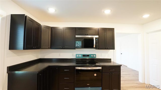 kitchen featuring stainless steel appliances, dark countertops, light wood-style flooring, dark brown cabinets, and recessed lighting